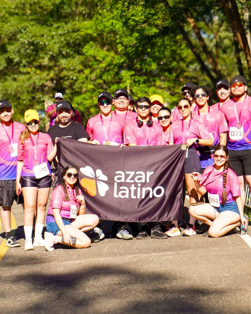 Equipo de Azar Latino Social junto a su bandera en la Corrida Octubre Rosa 2026.